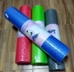 Tapetes de yoga enrollados en colores azul, rosa, verde y gris con textura tejida.