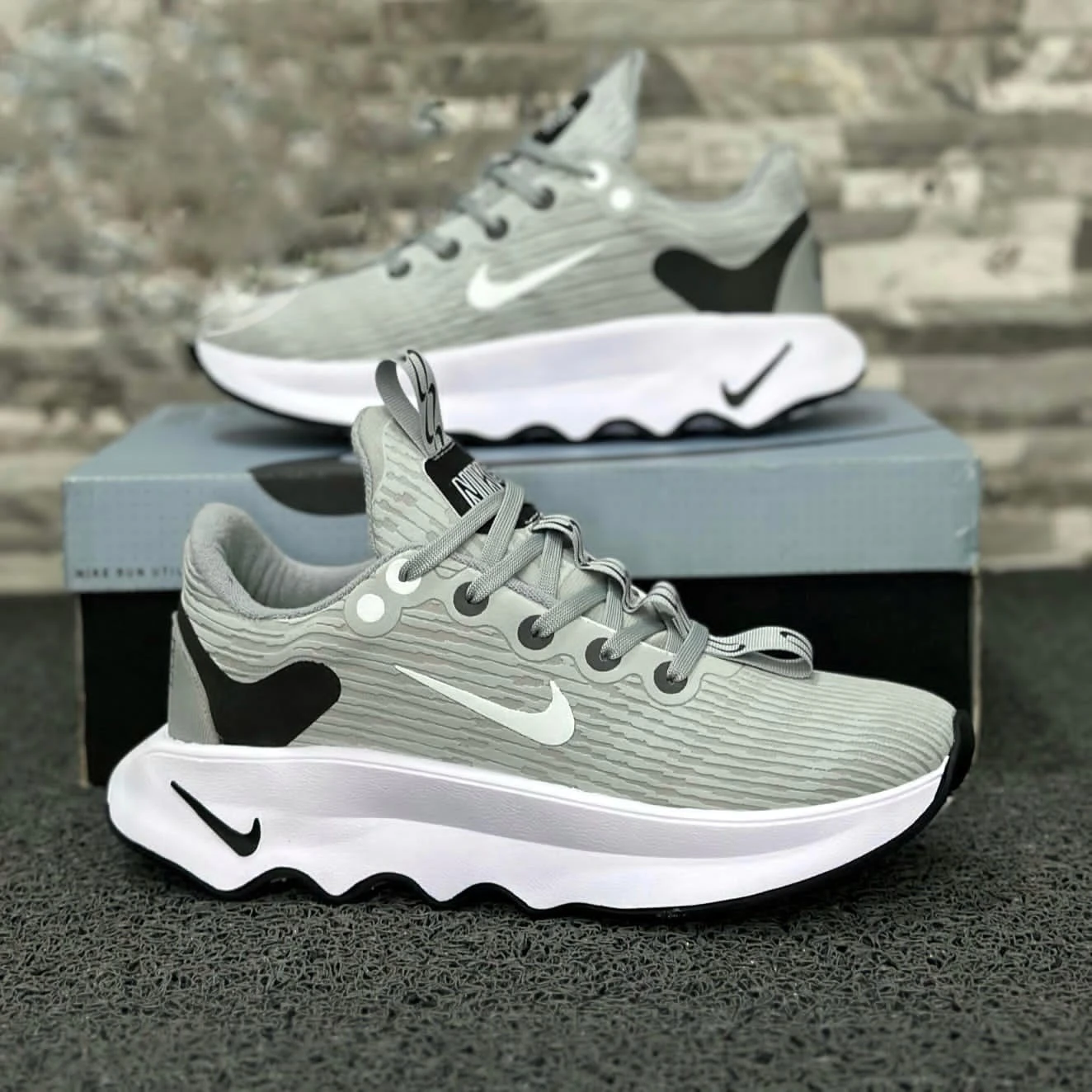 Zapatillas Nike Cabello grises con detalles blancos y negros, suela blanca ondulada.