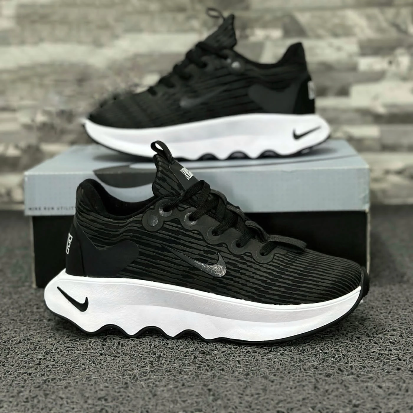 Zapatillas Nike negras con suela blanca ondulada, diseño moderno y detallado.