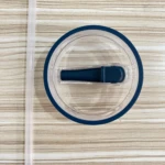 Tapa antiderrame azul para termo Stanley y pitillo transparente sobre fondo de madera.