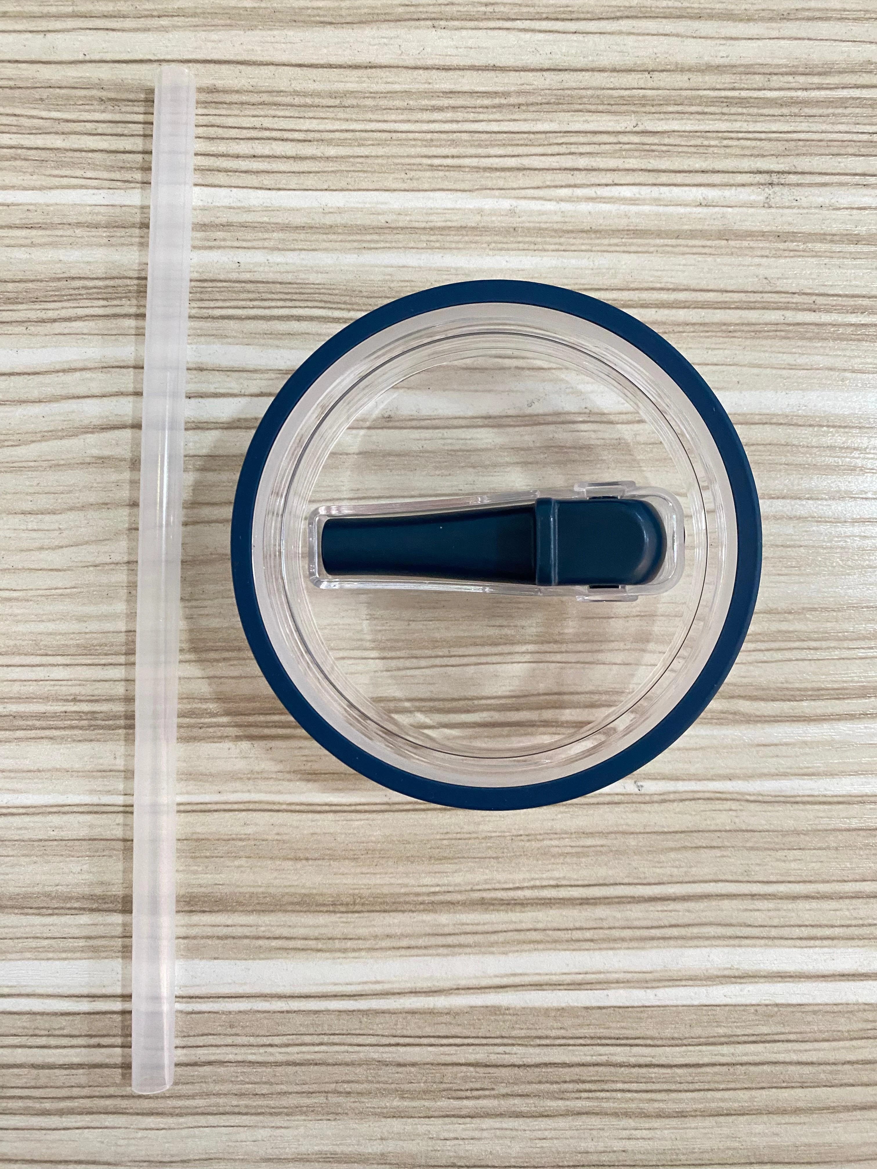 Tapa antiderrame azul para termo Stanley y pitillo transparente sobre fondo de madera.