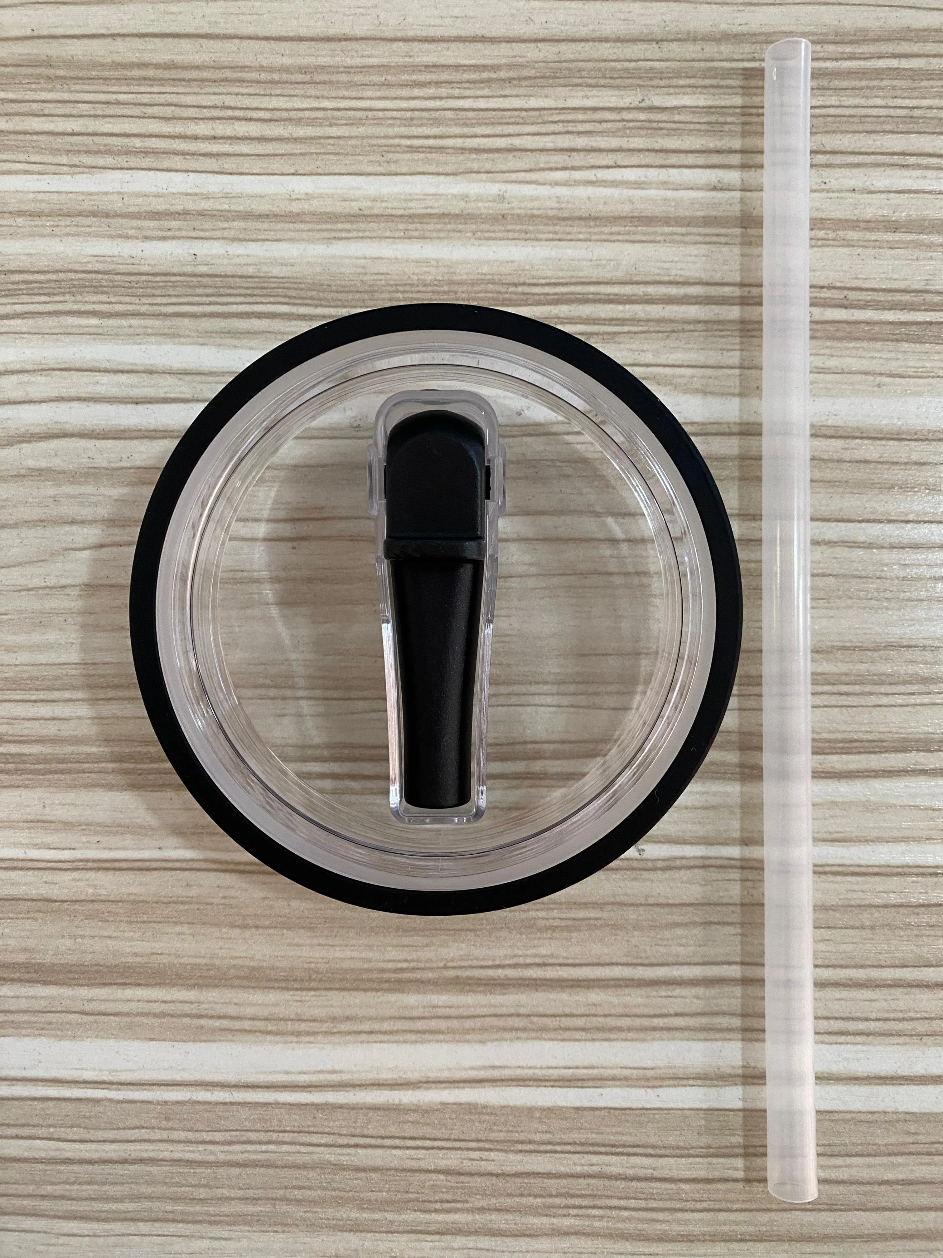 Tapa para termo Stanley con sorbete y sello negro, fondo de madera.