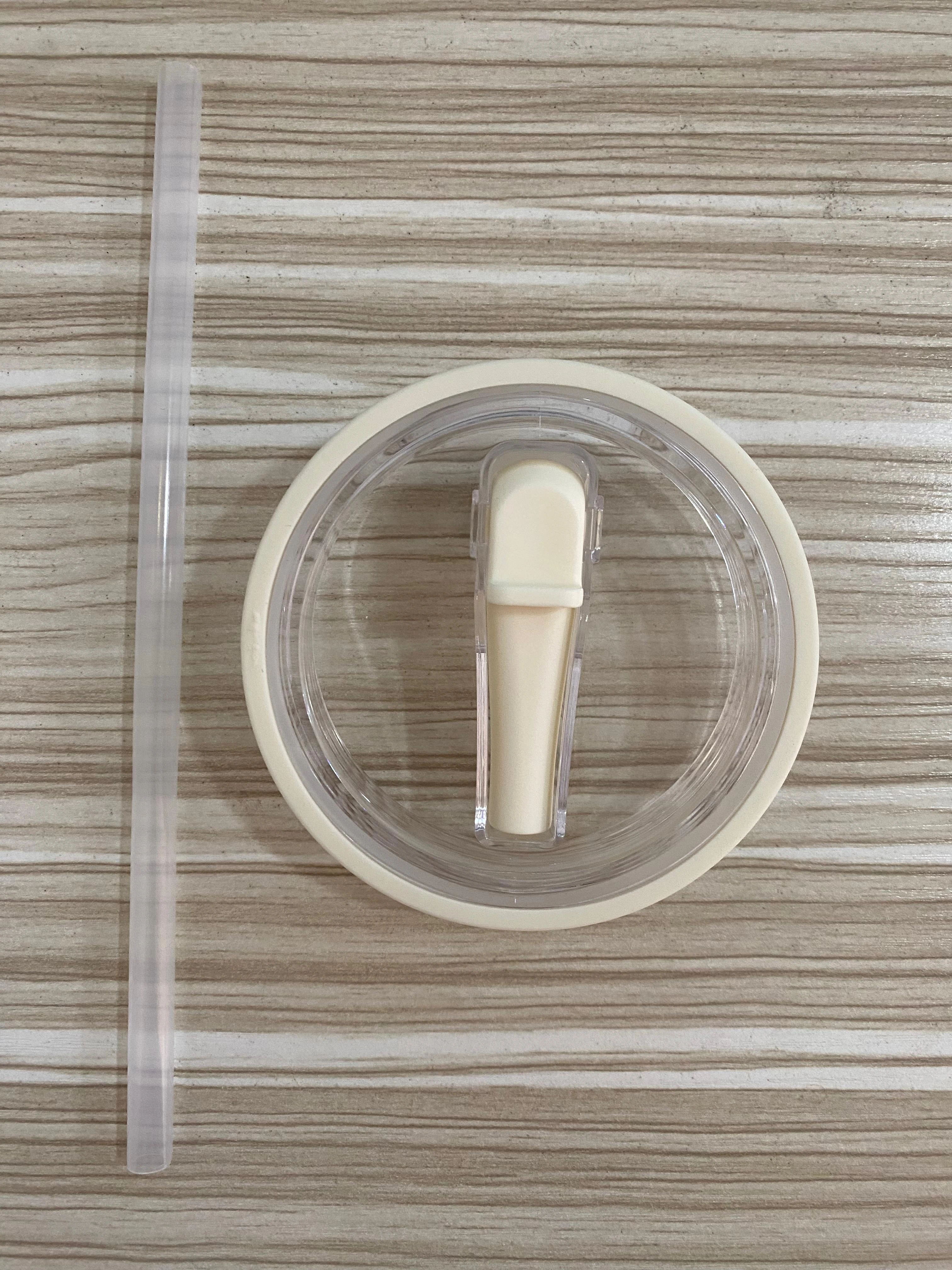 Tapa blanca con bombilla transparente para termo Stanley, vista superior, sobre fondo texturizado madera.