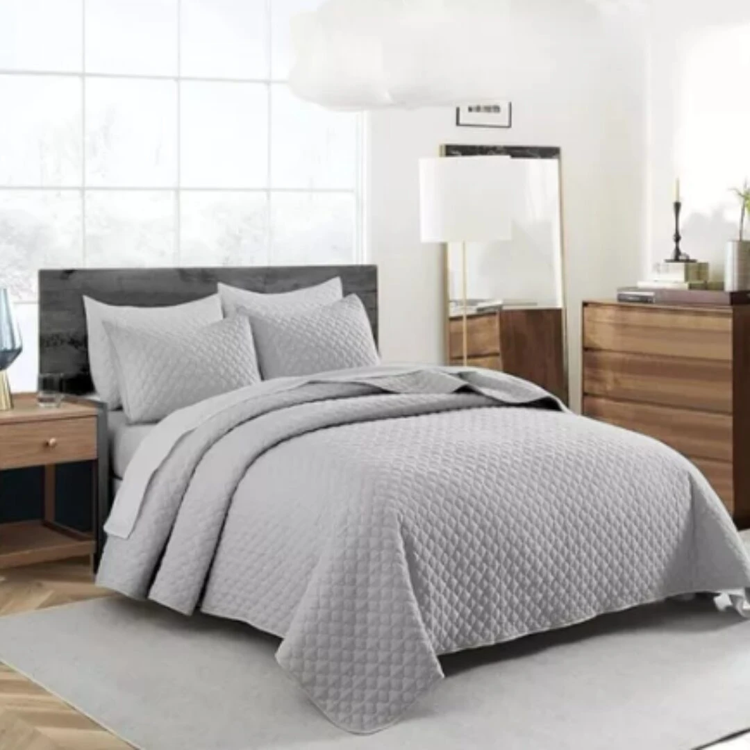 Colcha española doble faz gris con textura acolchada en cama matrimonial, con almohadas a juego.