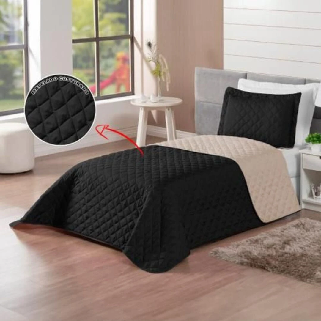 Colcha española doble faz negra y beige, acolchada con diseño rombos, sobre cama.