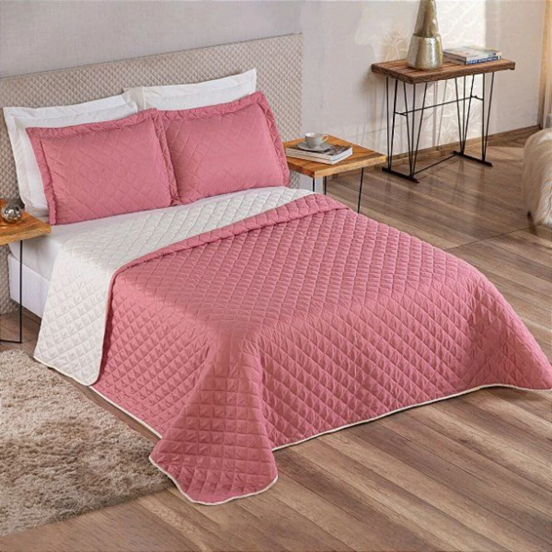 Colcha española doble faz rosa y blanca, acolchada con diseño de rombos, vista frontal de cama.