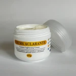 Tarro blanco de 60g de crema aclarante con tapa abierta al lado, mostrando textura cremosa en el interior y etiqueta con detalles sobre el uso en piel.