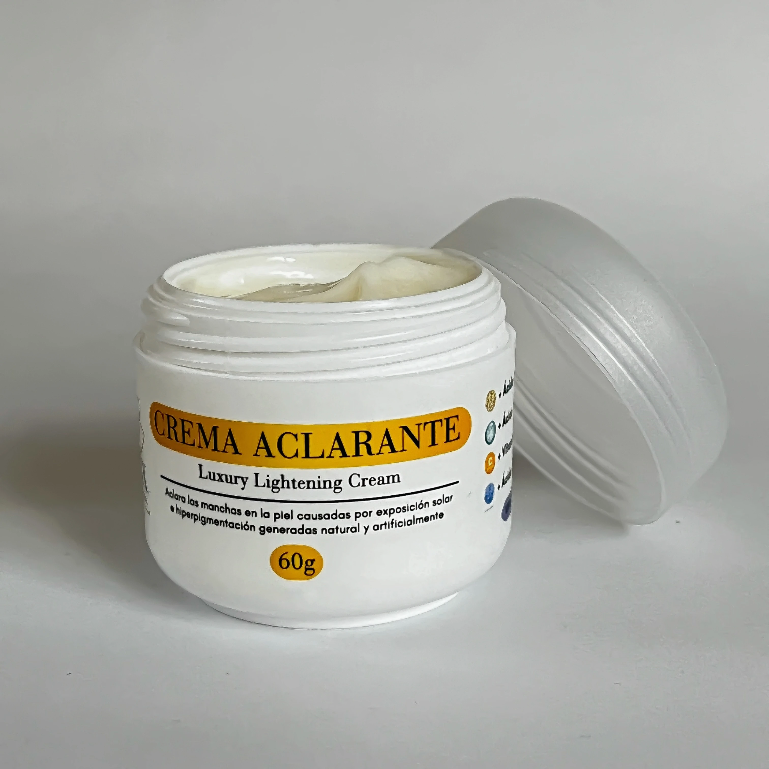 Tarro blanco de 60g de crema aclarante con tapa abierta al lado, mostrando textura cremosa en el interior y etiqueta con detalles sobre el uso en piel.