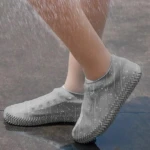 Botas de lluvia cortas grises impermeables con suela antideslizante, cubriendo pies en ambiente lluvioso.