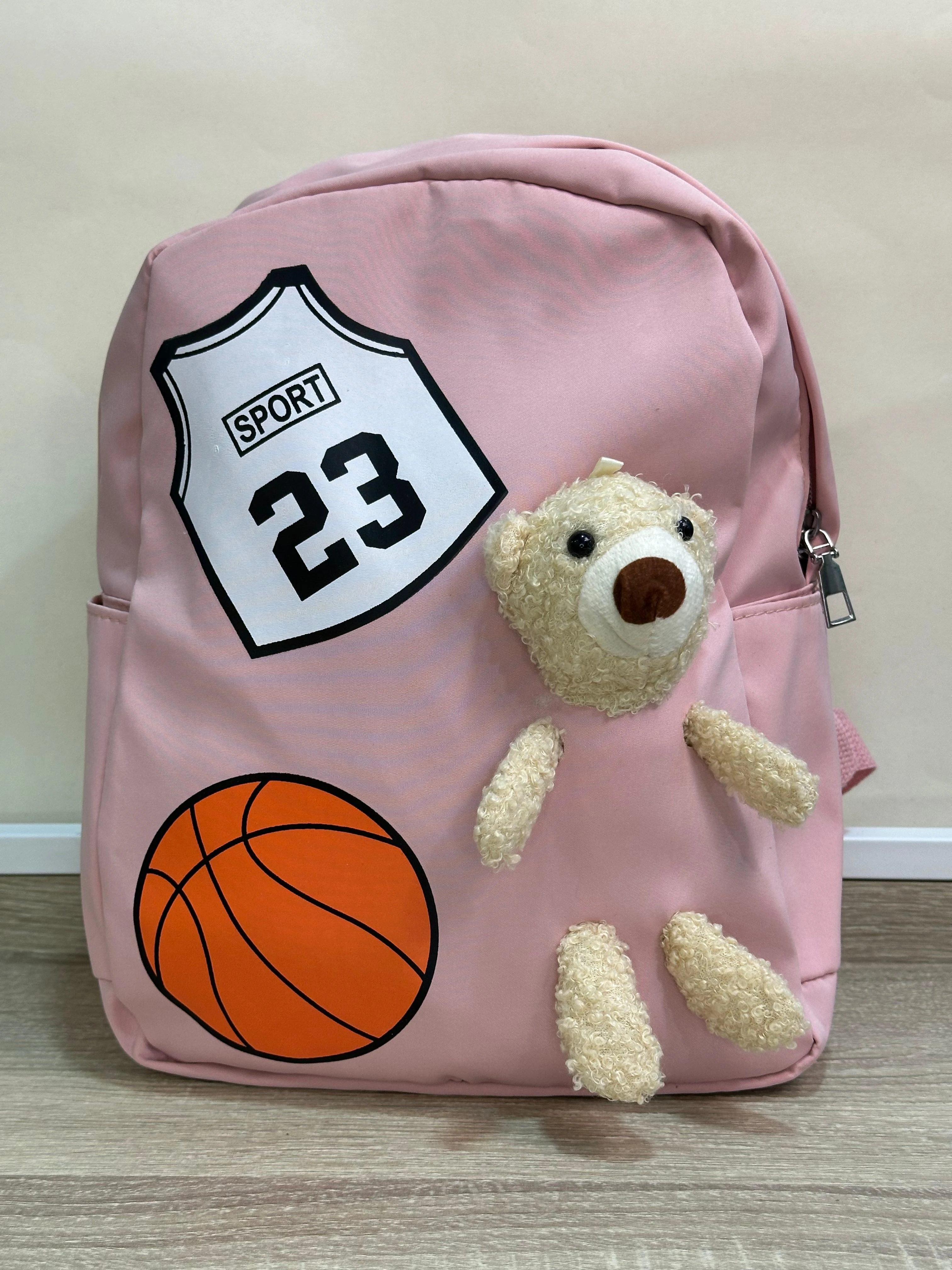 Mochila escolar rosa con apliques de oso de peluche, balón de baloncesto y número 23.