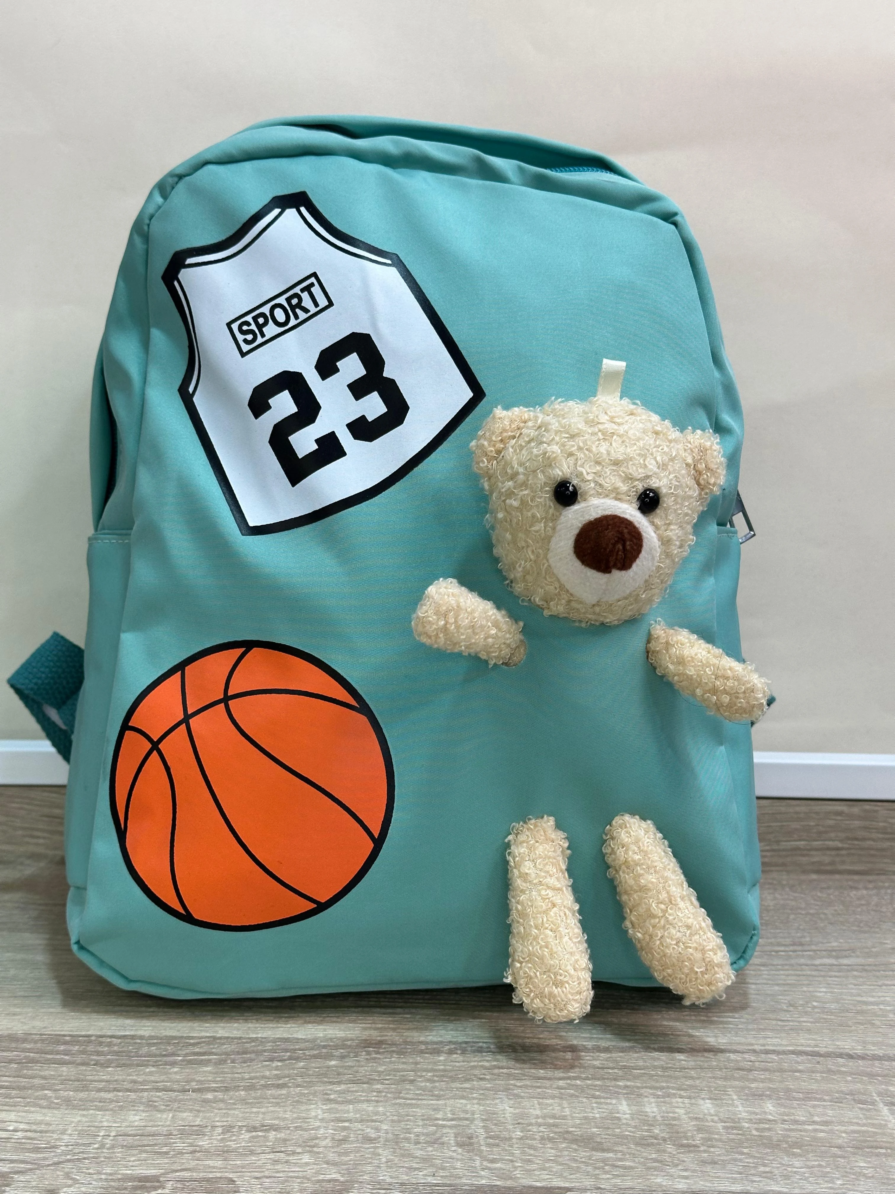 Mochila escolar azul con diseño de baloncesto y osito peluche.