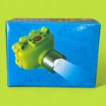 Linterna minera acuática Ak3511 verde con haz de luz azul, sobre caja con diseño de ondas y flores en azul.