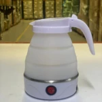 Hervidor de agua portátil blanco de silicona plegable con asa y botón de encendido.