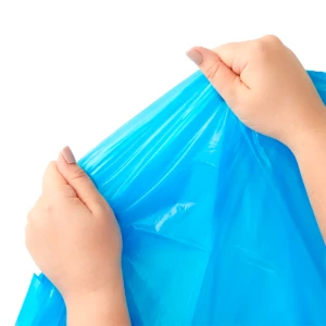 Manos sujetando capa impermeable infantil azul brillante, textura plástica lisa.