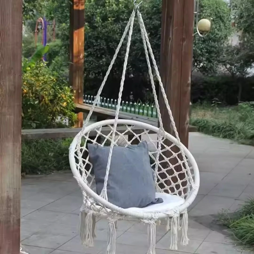 Silla hamaca colgante de macramé blanco con cojín gris, ideal para interiores y exteriores.