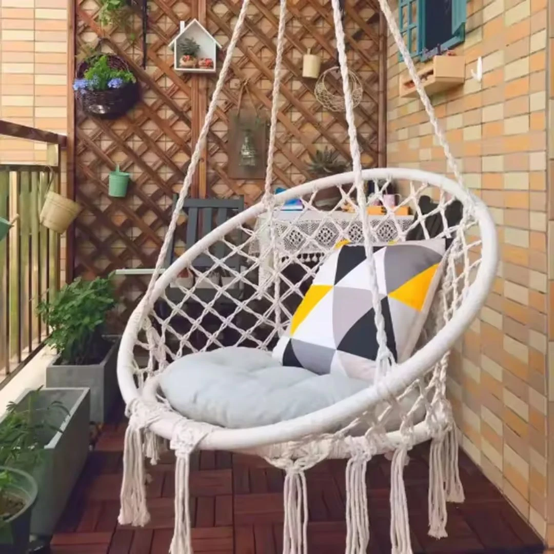 Silla hamaca colgante blanca de macramé con cojines y almohadón geométrico, ideal para balcón o terraza.