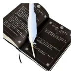 Libreta Death Note negra con pluma blanca y texto en páginas.