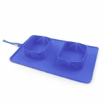 Comedero doble plegable de silicona azul con tapete antiderrames integrado y correa de ajuste, ideal para alimentación de mascotas en viajes y paseos.