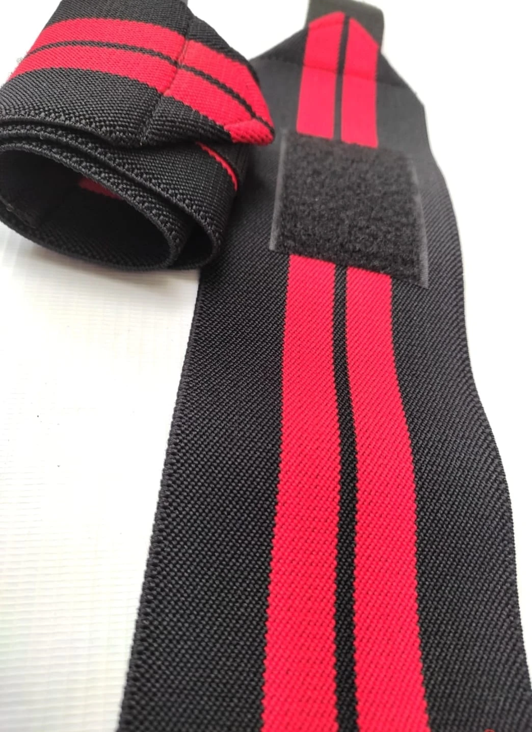 Muñequeras deportivas negras con líneas rojas, ajustables, con velcro, ideal para levantamiento de pesas.