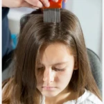 Niña con cabello castaño siendo revisada con peine fino para piojos.