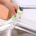 Extensor de grifo de cocina flexible blanco y verde, con chorro de agua disperso, en uso.