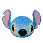 Lámpara de mesa decorativa con forma de cara de Stitch, acabado azul brillante tipo escarcha, orejas rosadas y luz interna encendida sobre fondo blanco.