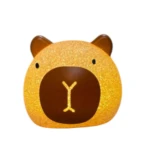 Lámpara de mesa decorativa estilo Kawaii con forma de carpincho, superficie texturizada en tono dorado brillante y detalle de nariz en color café oscuro.