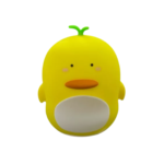 Lámpara nocturna de silicona blanda en forma de pollo amarillo, con brote verde en la cabeza, barriga blanca, ojos pequeños y pico naranja.