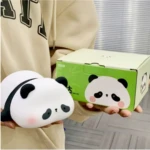 Lámpara de noche de silicona con forma de panda recargable, sostenida por una persona junto a su caja de empaque con diseño decorativo verde.