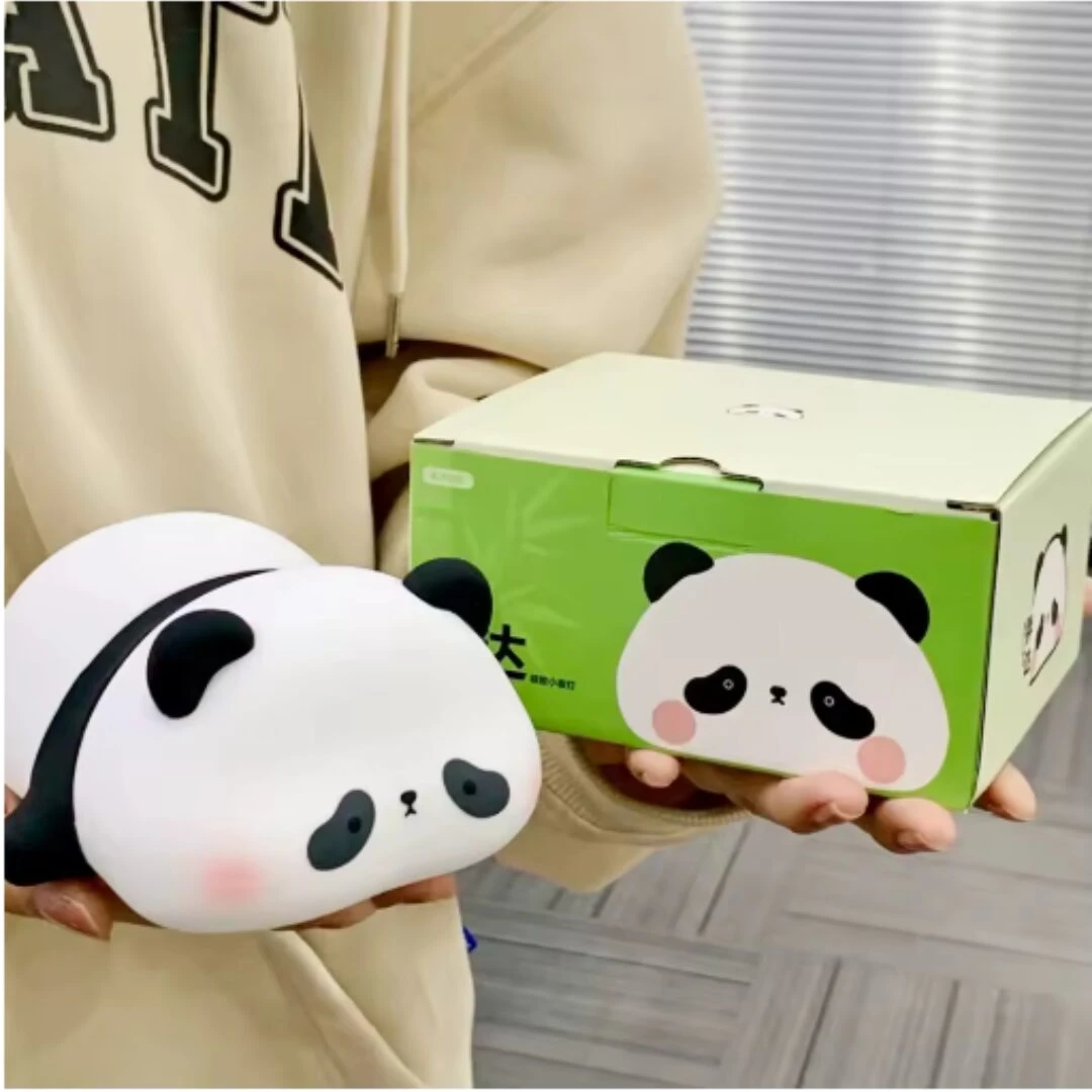 Lámpara de noche de silicona con forma de panda recargable, sostenida por una persona junto a su caja de empaque con diseño decorativo verde.