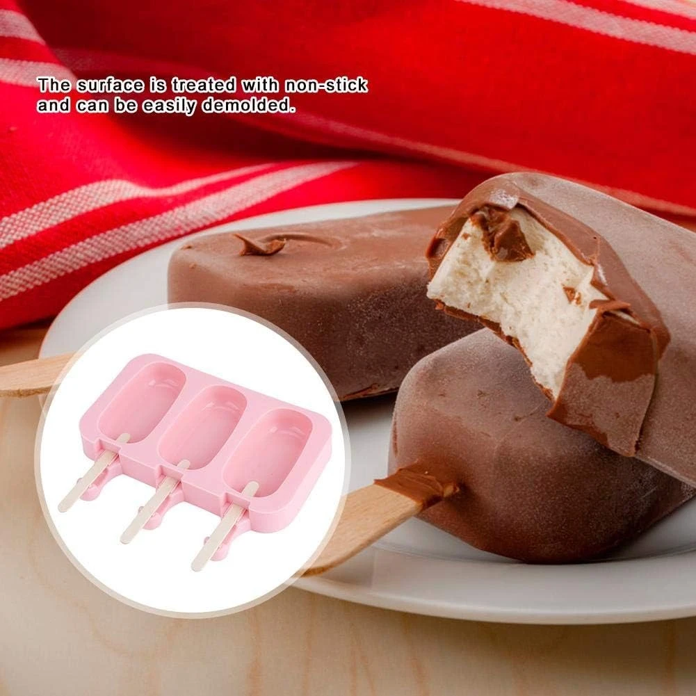 Molde de silicona rosado con tres cavidades para paletas, diseño antiadherente para desmoldar fácilmente, junto a paletas de chocolate caseras terminadas.