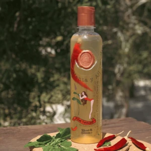 Shampoo control caspa Aji y Menta Ritual Botanico 400ml. Botella transparente con ají rojo entero. Fondo natural.