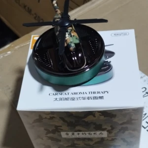 Ambientador solar para auto con diseño de helicóptero camuflado, sobre caja de producto.