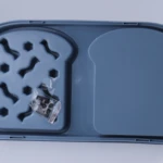 Plato antiahogo para mascotas en azul, con compartimentos para comida y bebedero, incluye bolsa con accesorios negros.