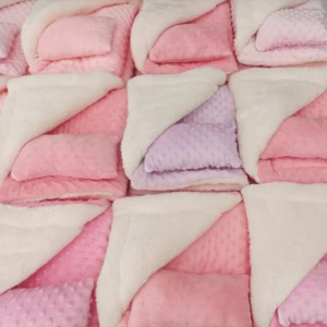 Cobija térmica rosa y lila con almohada incorporada, texturas suaves y acolchadas.