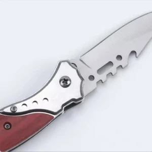 Navaja táctica con hoja de acero inoxidable, mango rojo y detalles metálicos.