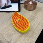 Cepillo masajeador amarillo con cerdas naranjas, ideal para quitar pelos en superficies de madera.
