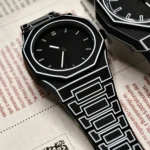 Reloj de pulso estilo caricatura 2D en silicona negra con bordes blancos, diseño geométrico y correa de eslabones sobre fondo de periódico con código QR.