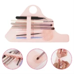 Guante rosado para maquillador con compartimentos para brochas y almohadilla limpiadora.