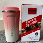 Vaso termo de acero inoxidable color rosa degradado a blanco, junto a su caja con frases motivacionales.