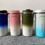 Set x2 vasos térmicos para bebidas calientes, degradado azul, rosa, verde y blanco, tapa negra y rosa, sobre alfombra gris.