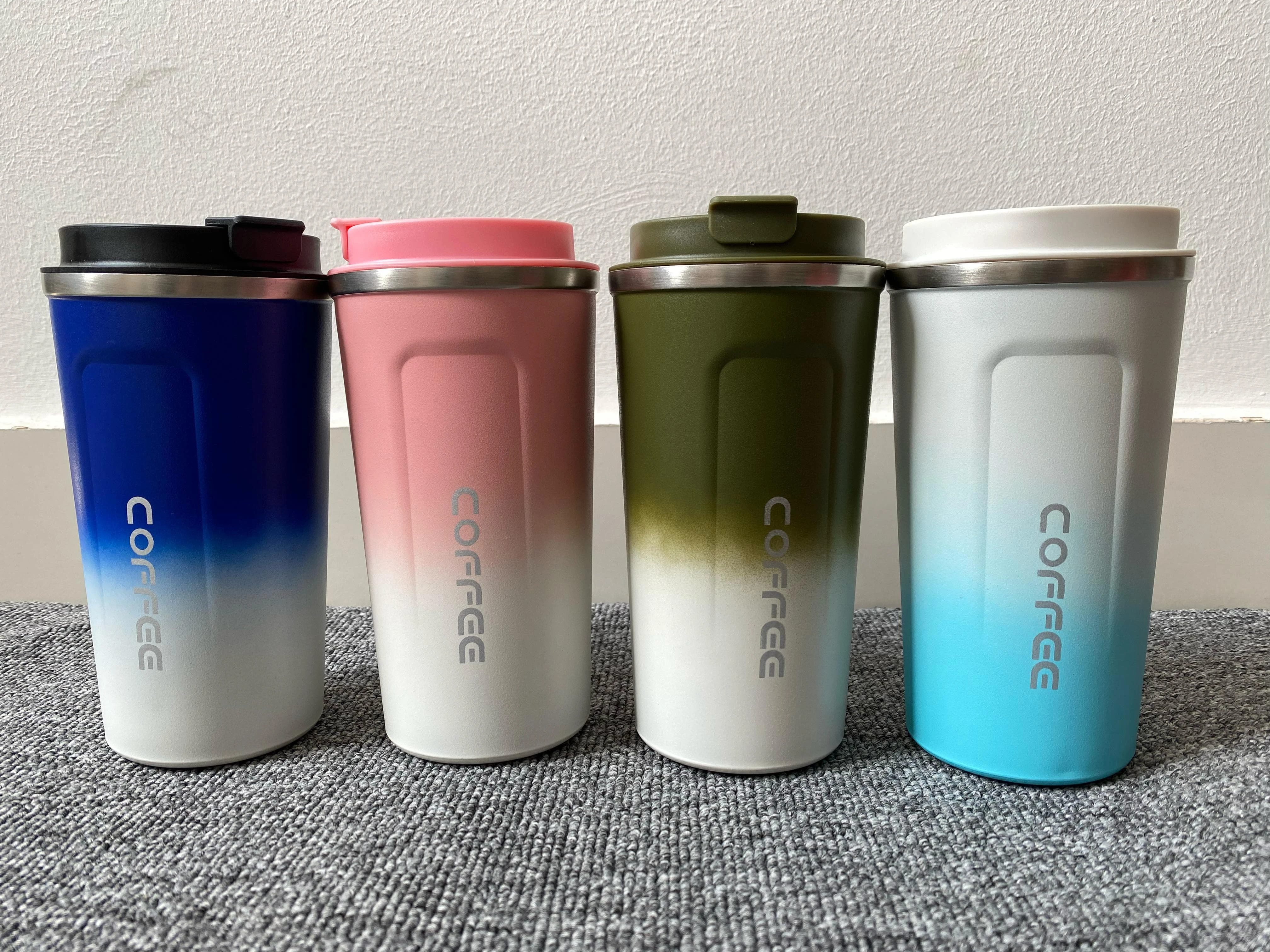 Set x2 vasos térmicos para bebidas calientes, degradado azul, rosa, verde y blanco, tapa negra y rosa, sobre alfombra gris.