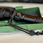 Linterna LED negra recargable de 2500 lúmenes en estuche verde con cable USB.