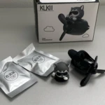 Ambientador para carro negro en forma de avión con figura de perro piloto y dos paquetes de fragancia.