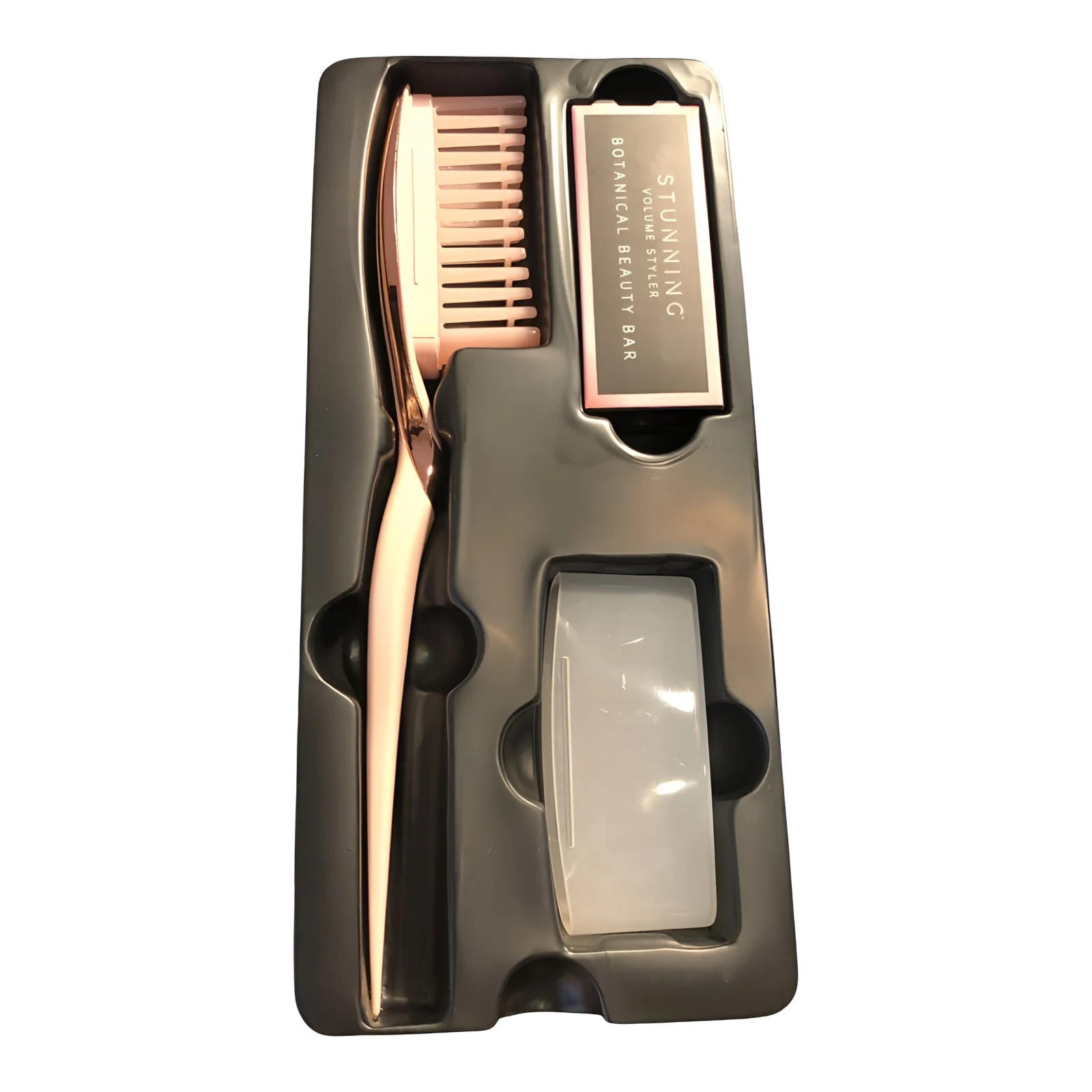 Set de cepillo voluminizador con mango rosado, barra de estilo botánico y accesorio protector dentro de una bandeja organizadora plástica gris.