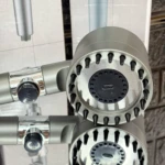 Cabezal de ducha plateado de alta presión con botón de parada y múltiples chorros negros, ideal para baño.