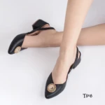 Zapatos destalonados negros para mujer con tacón bajo cuadrado y detalle circular dorado con apliques brillantes en la punta sobre fondo blanco.