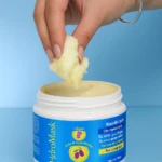 Mano saca mascarilla capilar HidroMask de tarro blanco. Textura cremosa, ideal para cabello.