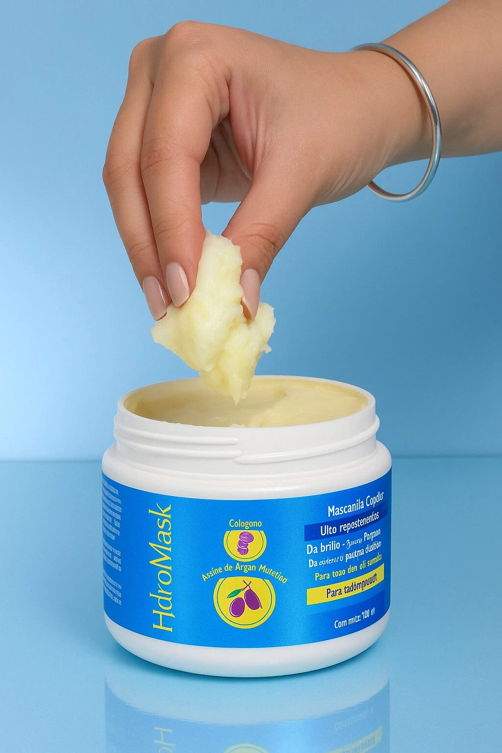 Mano saca mascarilla capilar HidroMask de tarro blanco. Textura cremosa, ideal para cabello.