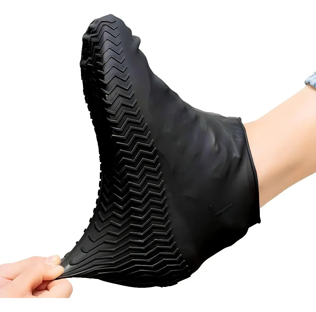 Zapato protector de silicona negra para lluvia, con suela antideslizante de relieve en zigzag, mostrado siendo estirado sobre un pie para probar su ajuste.